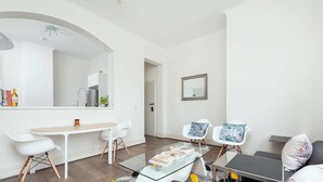 Un salon moderne avec une table basse en verre, des chaises blanches et un canapé.