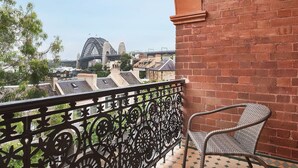 A balcony with a wrought iron railing, a wicker chair, and a view of a bridge and buildings. - Stunning Sydney Home 9 (Millers Point)