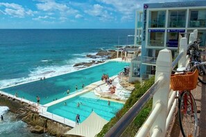 Un hotel frente al mar con una amplia zona de piscina, vistas al océano y un edificio con la señalización 'Bondi Icebergs'.