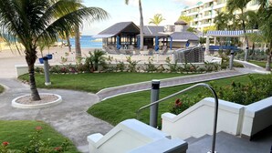 A resort with a pool area, lounge chairs, and a view of the beach. - Beachfront, ground level condo, steps away from beach, pool and relaxation! (Cole Bay)