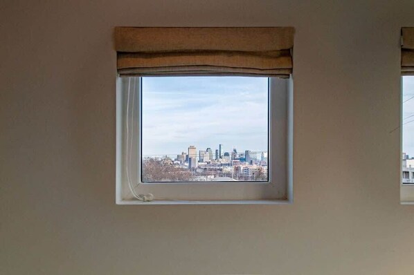Une pièce avec une fenêtre donnant sur le panorama urbain.