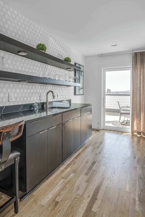 A modern kitchen with a black countertop, stainless steel cabinets, and a large window. - Modern Nashville Stay | Dual Rooftops (Nashville)