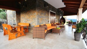 Un patio exterior con mobiliario de mimbre, paredes de piedra y vistas al paisaje.