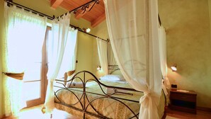 Un dormitorio con cama, cortinas, una mesita de noche y un tocador.