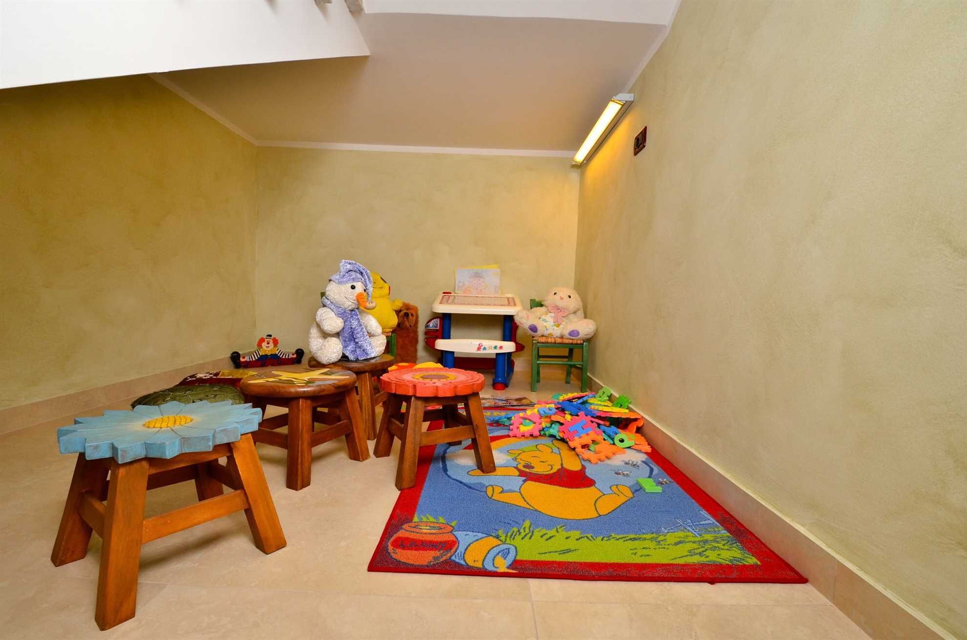 Ein Kinderspielbereich mit kleinen Tischen, Stühlen und einer Winnie-Puuh-Decke.