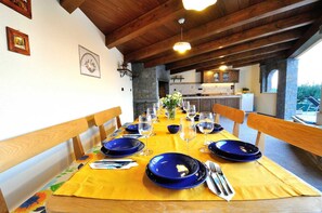 Ein Esstisch ist für eine Mahlzeit gedeckt, mit blauen Tellern, Weingläsern, Holzkästen und einer gelben Tischdecke.