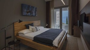 Ein modernes Hotelzimmer mit einem Holzbett, Meerblick und einem Flachbildfernseher.