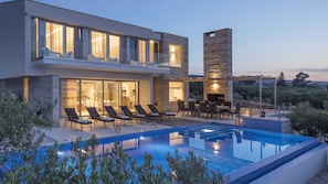 A modern house with a swimming pool, outdoor seating, and a stone fireplace. - Luxury Villa Spectrum with Heated Pool (Splitska)