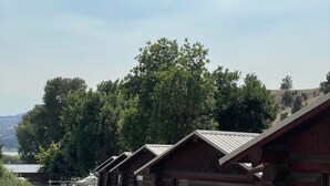 A row of log cabins with gravel paths, surrounded by trees and a clear sky. - Cozy Log Cabin #5 on Beautiful Canyon Ferry Lake (Helena)