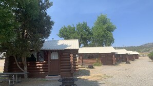 A row of log cabins with a gravel driveway and picnic tables. - Cozy Log Cabin #5 on Beautiful Canyon Ferry Lake (Helena)