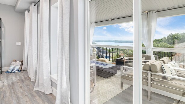 A balcony with a view of a lake, a seating area with cushions, and a wooden floor. - Large-group Retreat w/Hot Tub, 2 Kitchens, Grill (Branson)