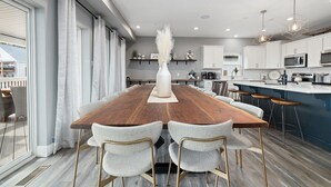 A modern kitchen with white cabinets, a wooden dining table, and bar stools. - Large-group Retreat w/Hot Tub, 2 Kitchens, Grill (Branson)