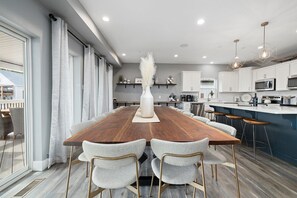 A modern kitchen with white cabinets, a wooden dining table, and bar stools. - Large-group Retreat w/Hot Tub, 2 Kitchens, Grill (Branson)