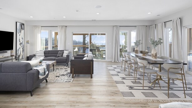 A spacious living room with a large sofa, a coffee table, and a dining area with chairs and a table. - Stunning Lake Views, Pool, Dream Kitchen, Grill (Branson)