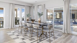 A modern dining area with a large table, six chairs, and two decorative vases. - Stunning Lake Views, Pool, Dream Kitchen, Grill (Branson)