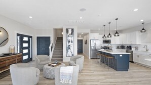 A modern kitchen with white cabinets, a central island with bar stools, and a staircase leading to another level. - Stunning Lake Views, Pool, Dream Kitchen, Grill (Branson)