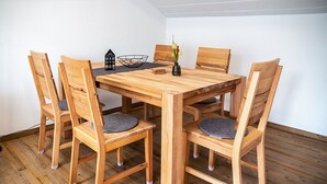 Ett matbord i trä med sex stolar, en svart dekorativ skål och en liten modell av ett hus som står på bordet.