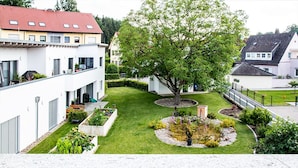 En bostadsgård med ett stort träd, en välskött gräsmatta och en liten trädgårdsyta.