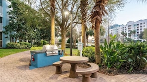 An outdoor patio with a grill, seating, and a sign indicating grill rules.