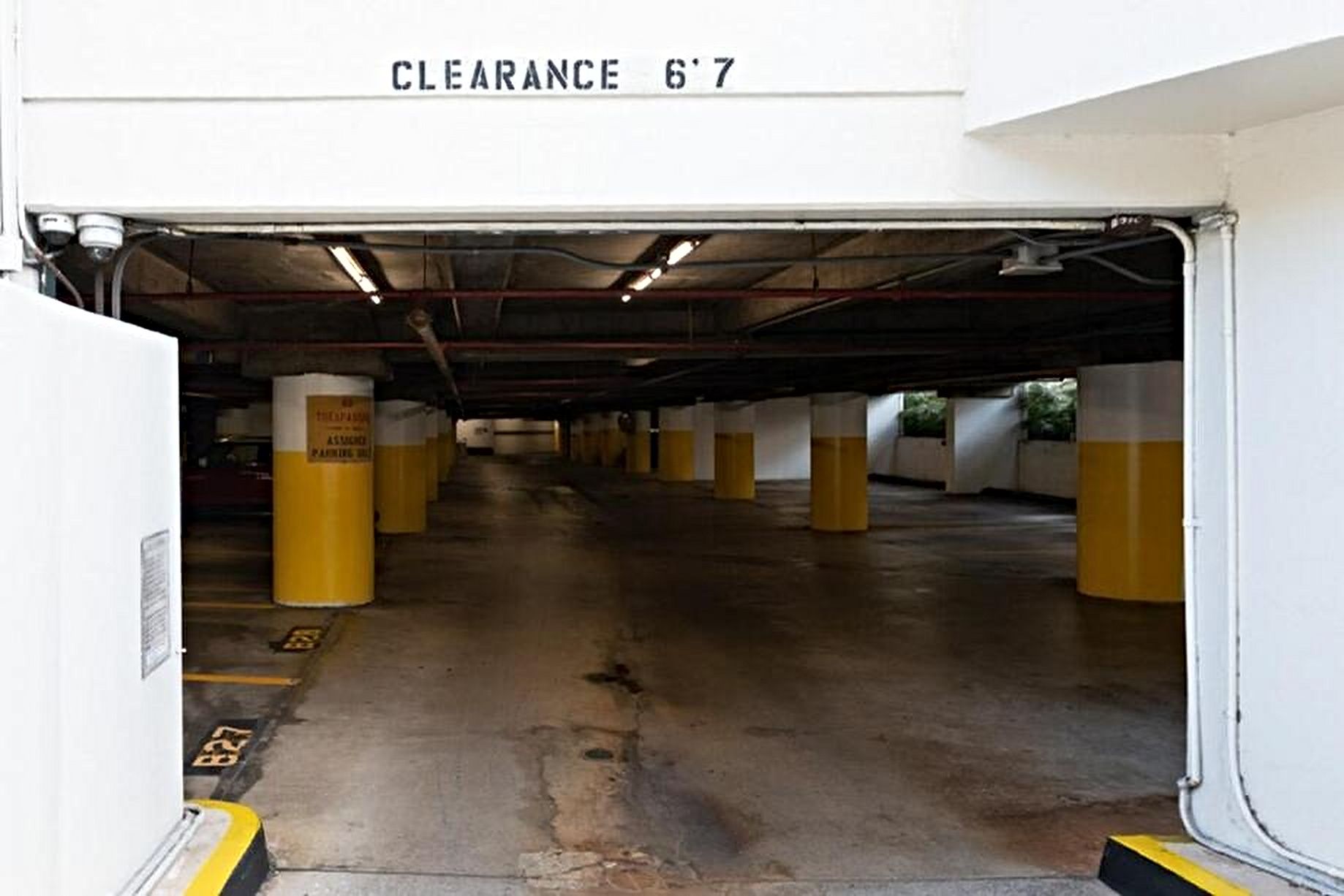 An underground parking garage with yellow bollards and a clearance sign of 6'7'.