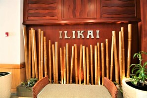Un espace d’accueil avec un mur en bambou et le nom « ILIKAI » inscrit au centre.