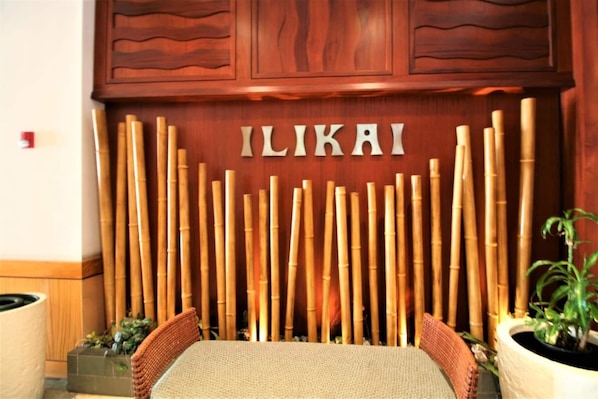 Un espace d’accueil avec un mur en bambou et le nom « ILIKAI » inscrit au centre.