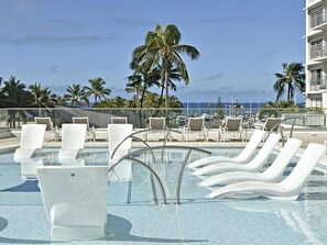 Un espace piscine avec des chaises longues et vue sur l’océan.