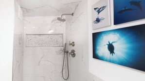 Een moderne badkamer met een douche, toilet en wastafel. Drie ingelijste foto's hangen aan de muur.