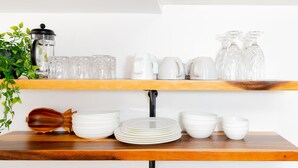 Een keukenkastje met witte keramieken borden, een houten lepel en een koffiezetapparaat.