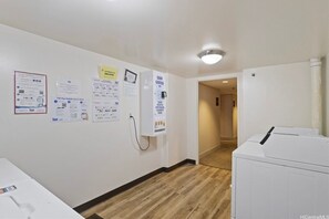 Un couloir comprenant un espace dédié à la buanderie, un coin pour le savon, et des affiches d’information accrochées aux murs.
