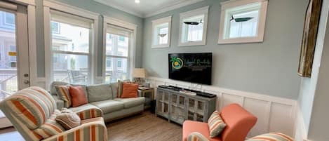 A living room with a sofa, armchairs, a TV, and a ceiling fan.