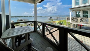 A covered outdoor area with a table and chairs, overlooking a body of water with docks and boats. - Flash Sale~Book Now~Tortuga Daybreak~Sleeps 8 (Gulf Shores)