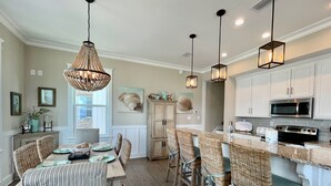 A spacious kitchen with white cabinets, a central island, and hanging pendant lights. - Flash Sale~Book Now~Tortuga Daybreak~Sleeps 8 (Gulf Shores)