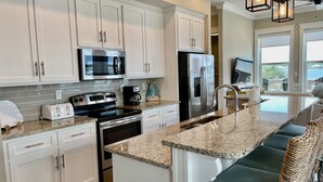 A modern kitchen with white cabinets, stainless steel appliances, a granite countertop, and a built-in island with seating. - Flash Sale~Book Now~Tortuga Daybreak~Sleeps 8 (Gulf Shores)