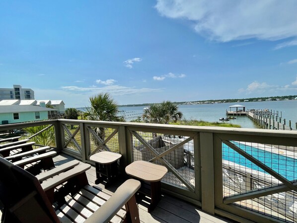 A deck with outdoor seating and a view of a lake and dock.