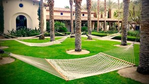 A courtyard with palm trees, a building with a tiled roof, and a hammock. - Stunning 2bed/2bath Villa - Amazing Location+Views (La Quinta)