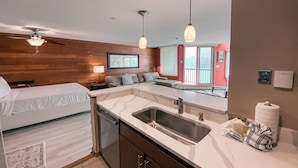 A compact hotel room with a kitchenette, a bed, a sofa, and a view of the outside. - Lakeside 1497 (Keystone)