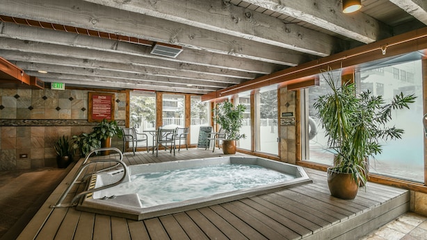 A wooden deck with a hot tub, potted plants, and a view of the outside. - Lakeside 1497 (Keystone)