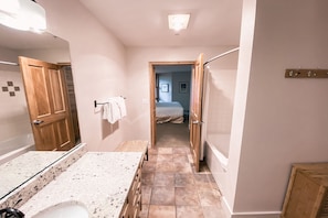 A modern bathroom with a large mirror, a granite countertop, and a shower area. - Silver Mill 8189 (Keystone)
