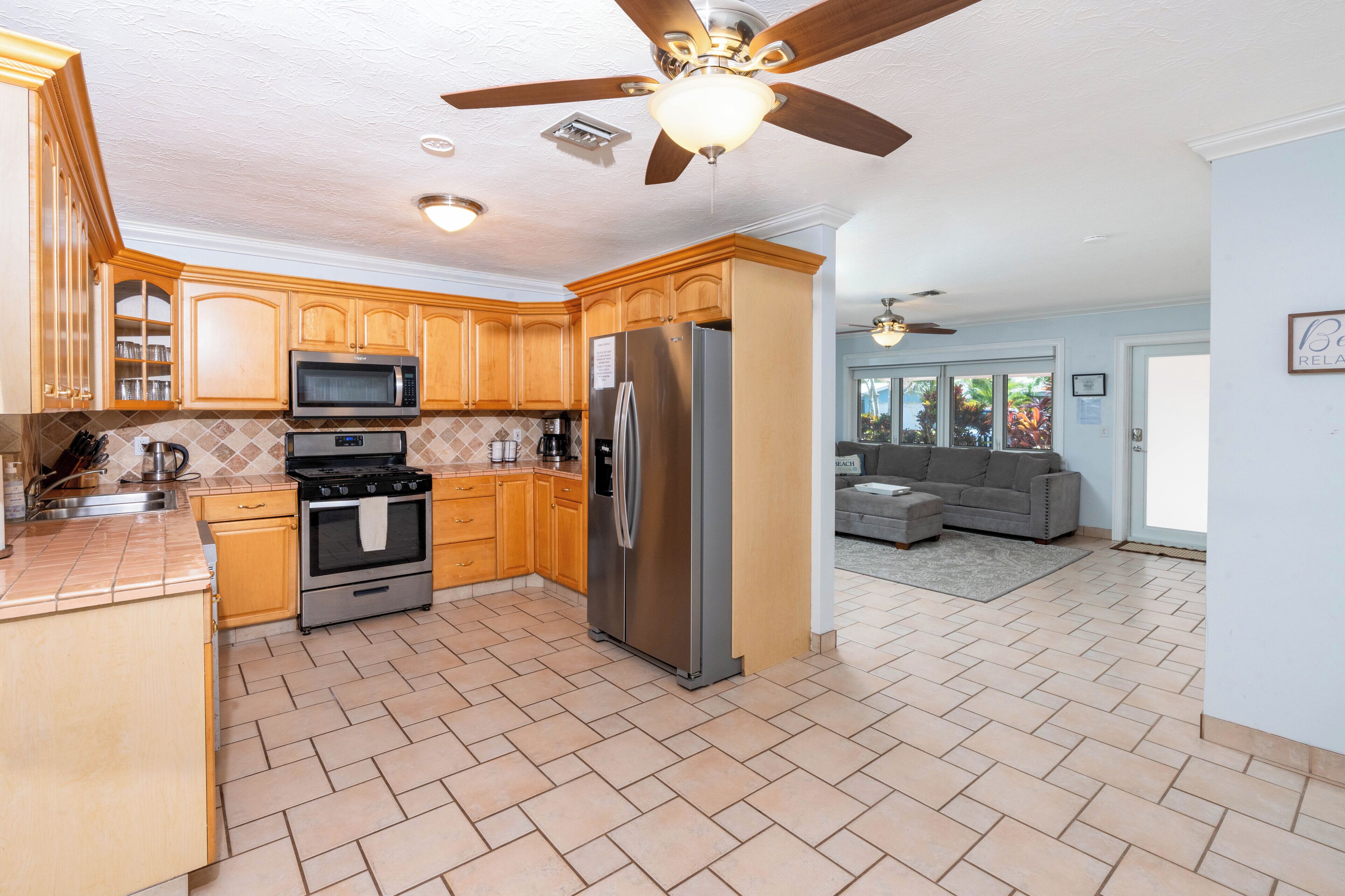 A kitchen with wooden cabinets, a stainless steel refrigerator, and a ceiling fan.