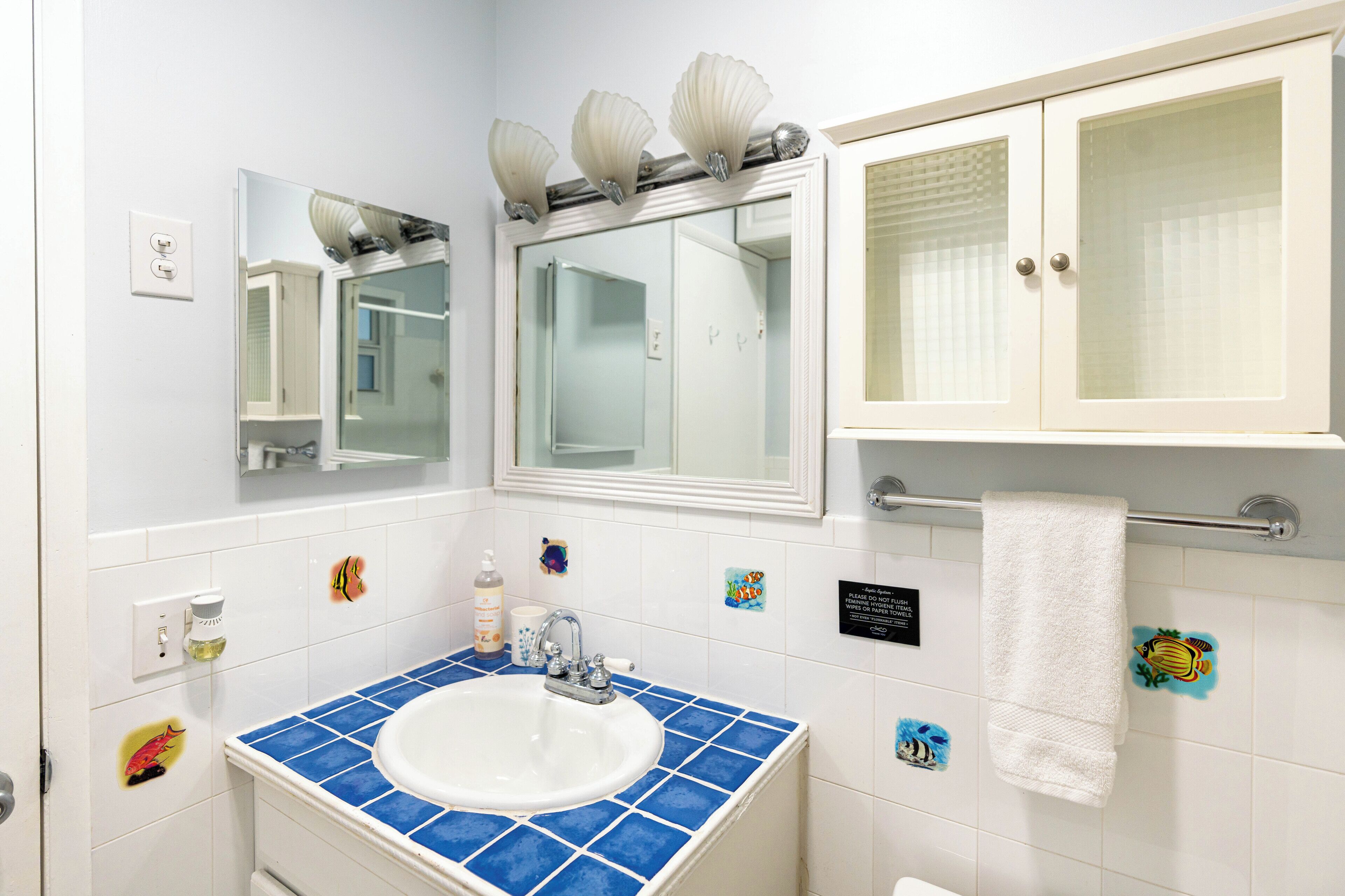 Un baño con un lavamanos blanco, azulejos azules, un espejo y un perchero para toallas.