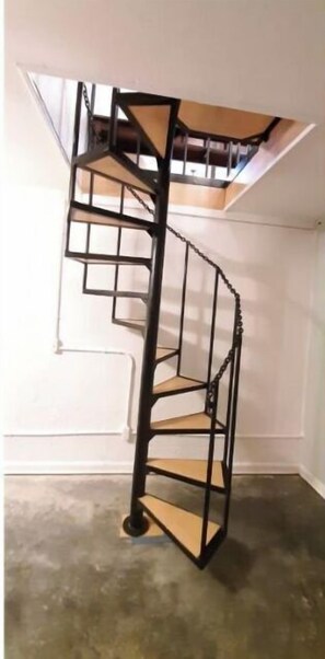 A spiral staircase with a metal frame and wooden steps, leading to an upper floor. - Lakefront Home- PETS, firepit, jukebox, pool table, canoe, kayak (Crossville)