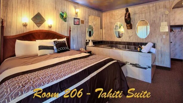 A hotel room with a bed, a vanity with a mirror, and a small kitchenette.
