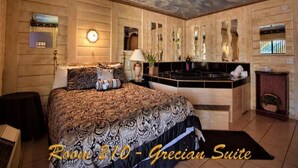 A room with a large bed, a vanity with a mirror, and a small table with a lamp.