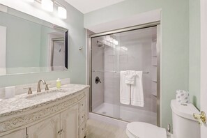 A bathroom with a marble vanity, a glass shower enclosure, and a toilet. - 27090 Belle Rio Dr (Bonita Springs)