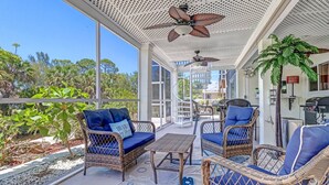 A covered outdoor seating area with wicker furniture and a ceiling fan. - 27090 Belle Rio Dr (Bonita Springs)