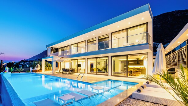 Ein modernes, zweistöckiges Gebäude mit Pool, Außenbereich und Blick auf Berge.