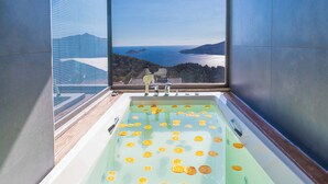 Eine Badewanne mit darin schwimmenden Orangenscheiben, Blick aufs Meer und ein Fenster.