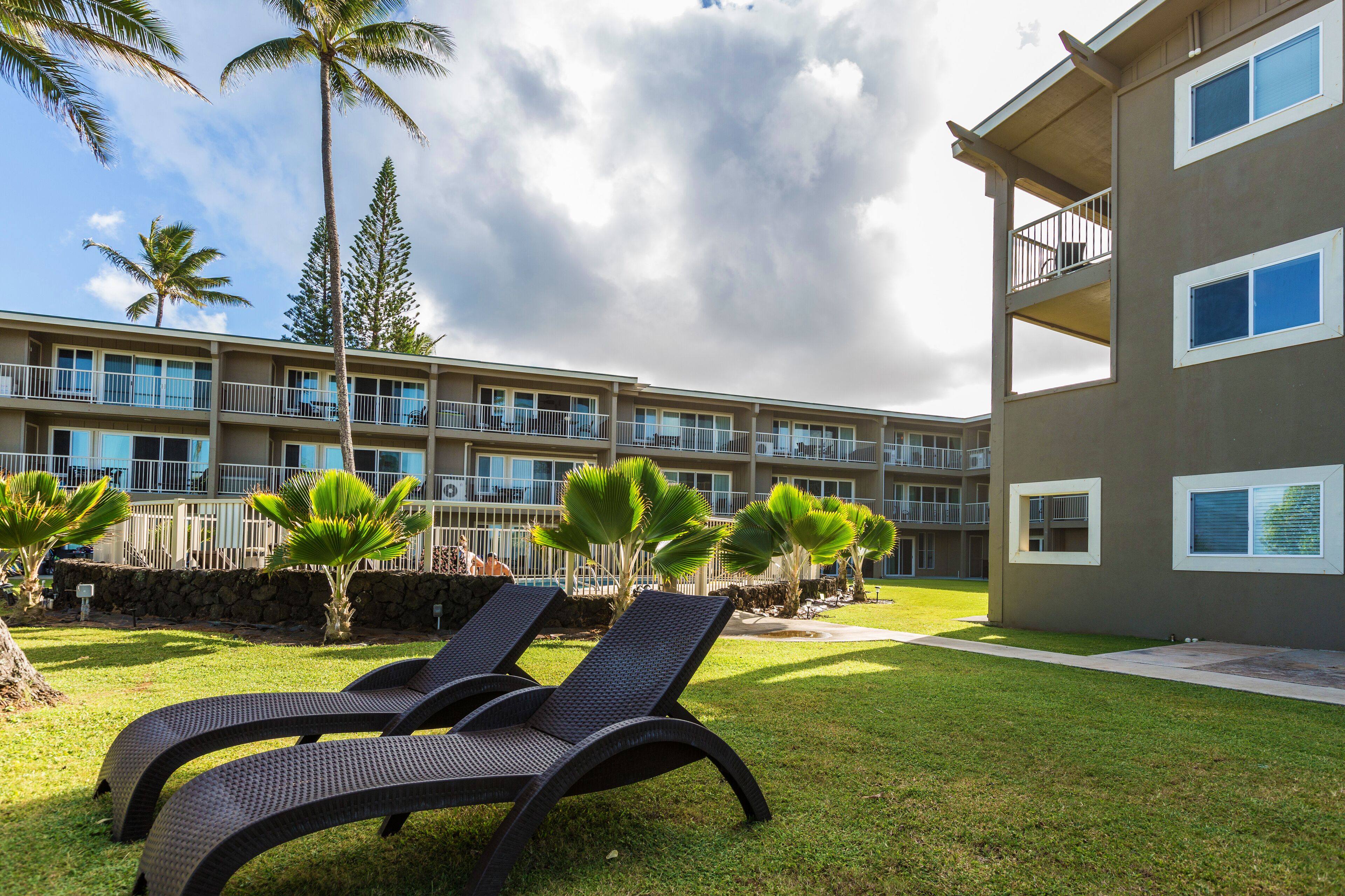 A hotel with a pool area, lounge chairs, and a view of the building's exterior.