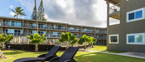 A hotel with a pool area, lounge chairs, and a view of the building's exterior.